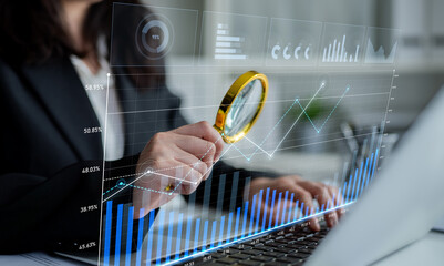 A business professional inspects financial data trends using a magnifying glass over digital charts in a modern office space, highlighting analysis and insight. Scalp