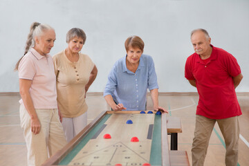 senior group Playing the board game of shuffleboard.  Kidult gaming in the gym. Active retirement...
