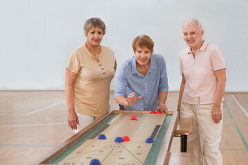 senior group Playing the board game of shuffleboard.  Kidult gaming in the gym. Active retirement...