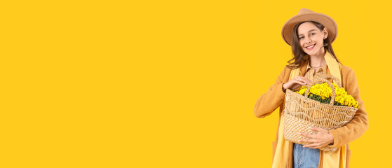 Stylish young woman with chrysanthemum flowers on yellow background