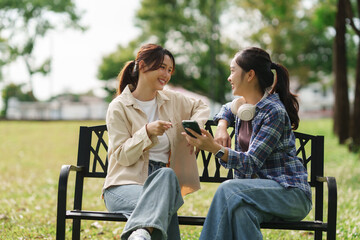 Young women friends sharing smartphone content smiling outdoors