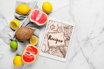 Digital recipe book and different fruits on light marble background
