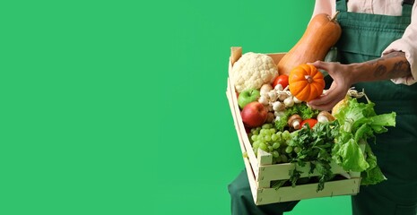 Male farmer with fresh vegetables and fruits on green background with space for text, closeup