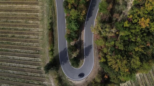 Curva strada in campagna, tornante di asfalto auto che percorre una curva vista aerea