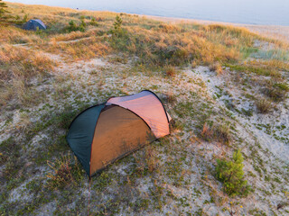 Aerial drone view of wild camping tents on sandy dunes by the Baltic Sea beach in Estonia....
