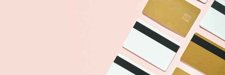 Gold and white credit cards arranged on pink background displaying payment concept.