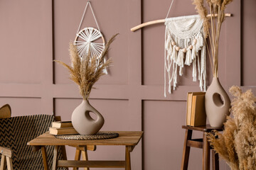 Vases with pampas grass and books on tables in room
