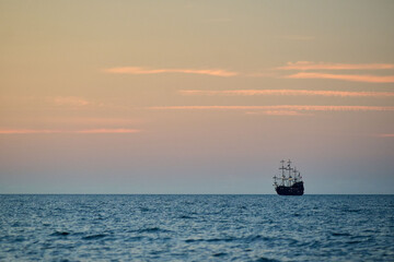 Tall ship silhouette on horizon at dusk, open ocean seascape, minimalist composition, tranquil maritime scene