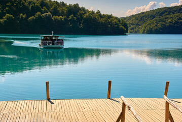 Wooden pier and dock extending into calm turquoise lake water at Plitvice Lakes National Park in...
