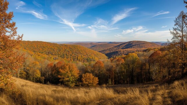 A scenic view of rolling hills covered in autumn foliage under a partly cloudy blue sky landscape scene