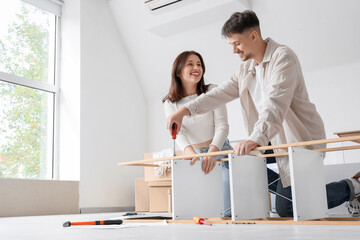 Obraz premium Young couple assembling shelf unit in bedroom on moving day