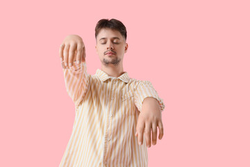 Male sleepwalker in pajamas on pink background