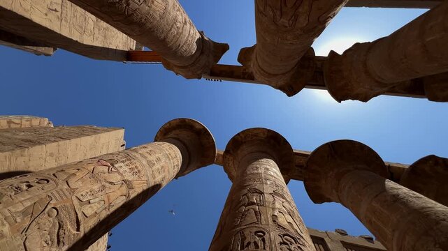 Low-angle panning shot of the massive columns in the Great Hypostyle Hall at Karnak Temple, Luxor, Egypt. For travel, history, or documentary use