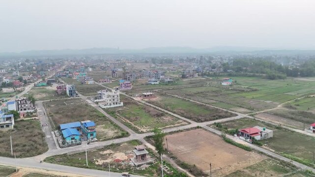 Aerial view of Devdaha Municipality near Butwal showing scattered houses, green farmland, and intersecting roads surrounded by open plots and semi-urban landscape under a hazy sky.