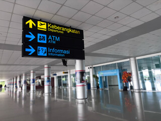 Airport sign directs passengers to departures, ATMs, and information within the terminal, providing clear guidance for travelers, ensuring smooth navigation and convenience.