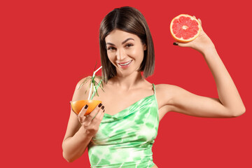 Beautiful young woman with grapefruit on red background