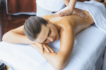 Obraz premium Caucasian woman customer enjoying relaxing anti-stress spa massage and pampering with beauty skin recreation leisure in day light ambient salon spa at luxury resort or hotel. Quiescent
