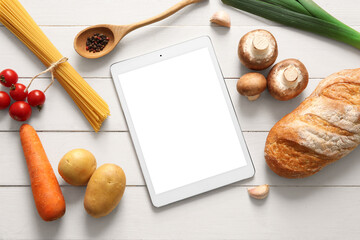Digital recipe book with spoon and ingredients on white wooden background