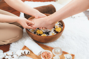 Woman indulges in blissful foot massage at luxurious spa salon while masseur give reflexology therapy in gentle day light ambiance resort or hotel foot spa. Quiescent
