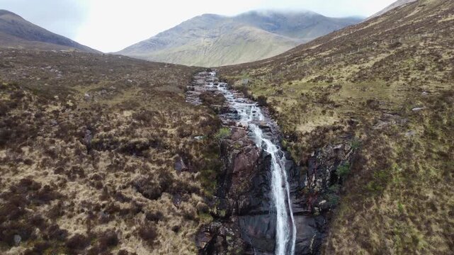 Majestic Eas a'Bhradain Waterfall flowing through rugged hills in the Scottish Highlands