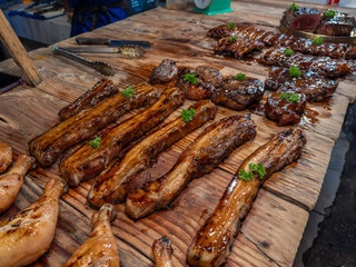 A tempting display of succulent grilled meats, including glazed pork belly, juicy ribs, and tender steaks, presented on a rustic wooden table. Perfect for savory culinary themes and market scene