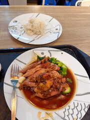A delicious, traditional Thai meal featuring tender braised pork leg (Khao Kha Mu) simmered in savory gravy, served with fresh Chinese broccoli, garlic cloves, and steamed jasmine rice on a wooden