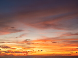 A breathtaking sunset over a vast ocean, showcasing a dramatic spectrum of warm hues. Fiery oranges, deep reds, and soft pinks paint the evening clouds, creating a serene and captivating natural
