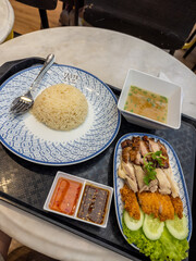 Authentic Hainanese chicken rice from 'Taste of the Island,' featuring succulent poached and crispy fried chicken, fragrant rice, clear broth, and two delicious sauces. A popular Southeast Asian