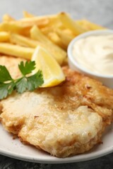 British Traditional Fish and chips with sauce, lemon and parsley on table, closeup