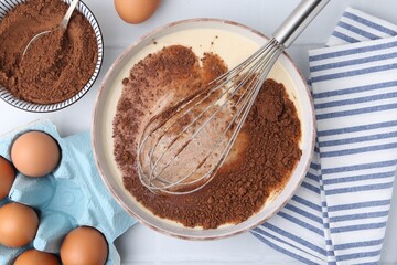 Adding cocoa powder into bowl with dough at white tiled table, flat lay