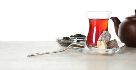 Traditional Turkish tea, delight and dry leaves on wooden table against white background