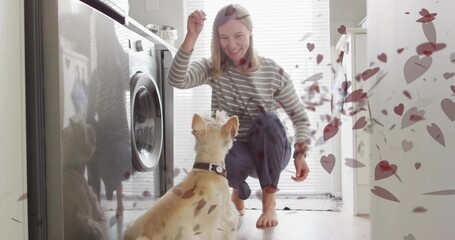 Holding treat, woman crouching in laundry area with front-load washer, dog collar, floating hearts