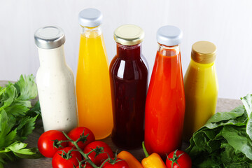 Bottles of different tasty sauces and products on grey wooden table, closeup