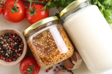 Bottles of different tasty sauces and products on white table, flat lay