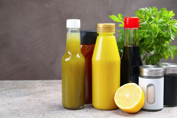 Bottles of different tasty sauces and products on grey table, closeup. Space for text