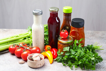 Bottles of different tasty sauces and products on grey table, closeup