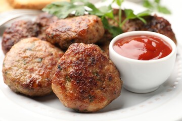 Delicious patties with parsley and ketchup on white plate, closeup