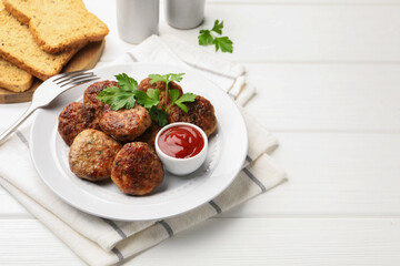 Delicious patties with parsley, ketchup and fork on white wooden table, closeup. Space for text