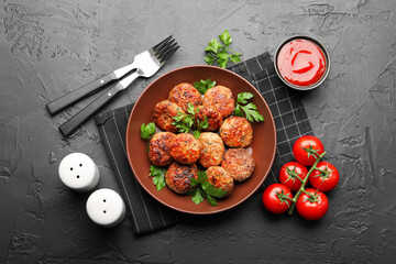 Delicious patties with parsley in bowl, tomatoes and ketchup served on dark textured table, flat lay