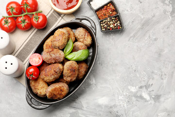 Tasty meat patties served on grey textured table, flat lay. Space for text
