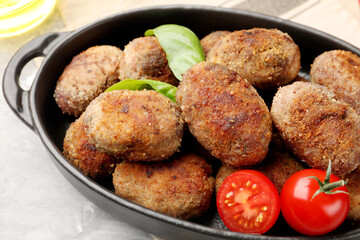 Tasty meat patties with basil and tomatoes on grey table, closeup
