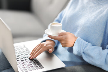 Woman with laptop during coffee break on sofa, closeup
