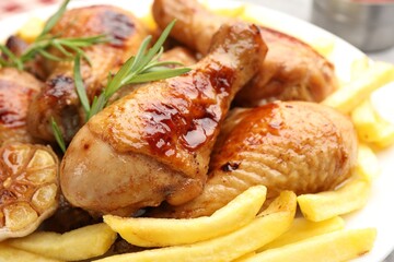 Grilled chicken drumsticks with french fries and spices on plate, closeup