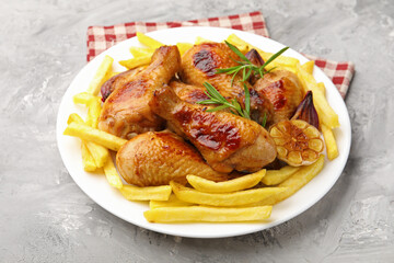 Grilled chicken drumsticks with french fries and spices on grey table, closeup
