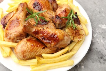 Grilled chicken drumsticks with french fries and spices on grey table, closeup