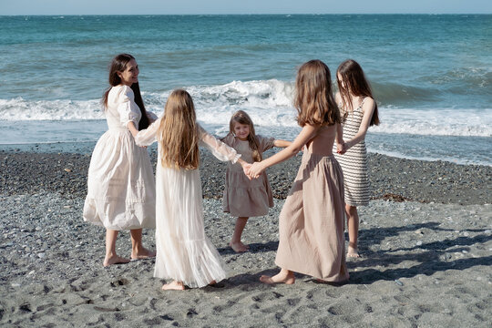 Mother and daughters dancing in a circle on the beach near the sea