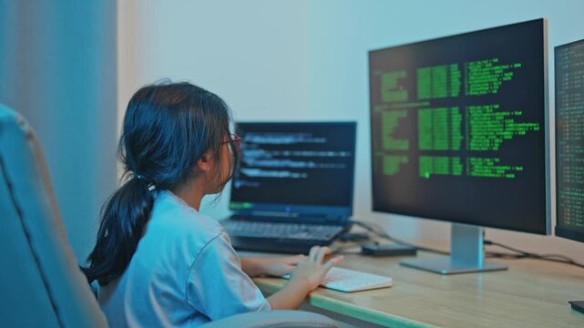 Young girl engages with computer code while programming at home, surrounded by multiple screens displaying coding languages and digital data