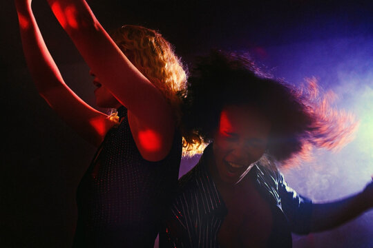 Happy couple dancing at nightclub in colorful disco lights
