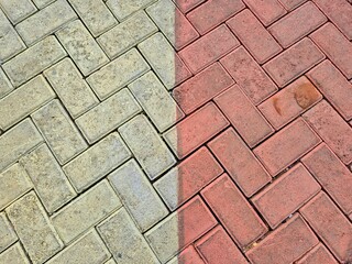 Striking visual contrast of clean and dirty herringbone paving stones, illustrating the dramatic impact of effective outdoor surface cleaning and maintenance
