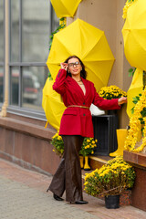 Portrait of a young woman with leaves in an autumn park. A stylish girl in a burgundy jacket strolls outdoors. Autumn fashion.